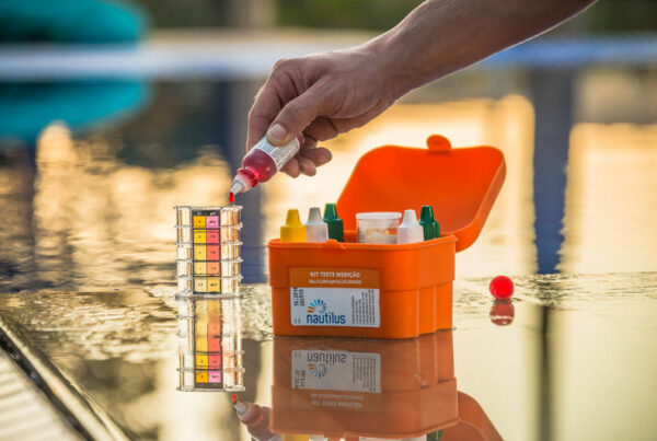 Mão pingando substância em recipiente com água para teste de pH da água