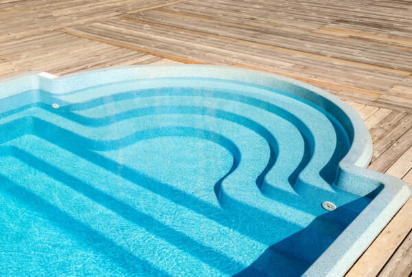 Ponta arredondada da piscina de fibra em um deck de madeira
